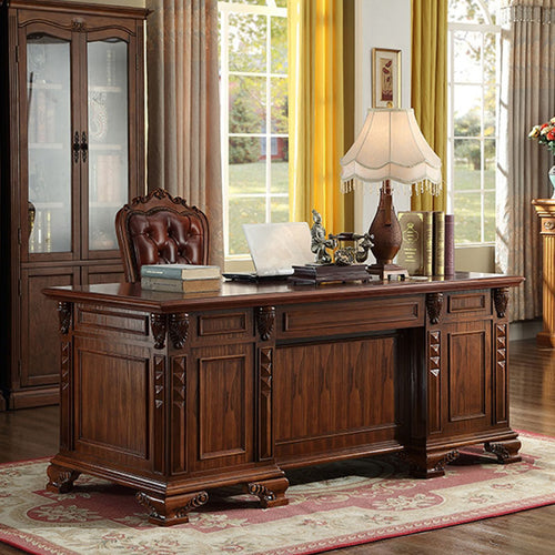 European carved solid wood executive desk with dark walnut finish in traditional office setting